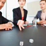 Business people throwing dice on conference room table.